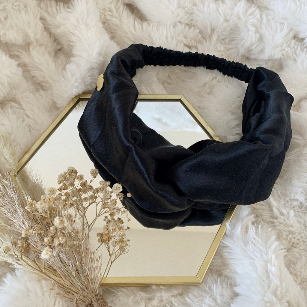 Flat lay of a black silk satin headband.