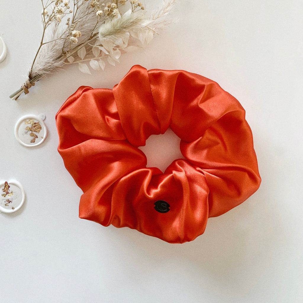 Flat lay of a jumbo size scrunchie in a bright tangerine colour.