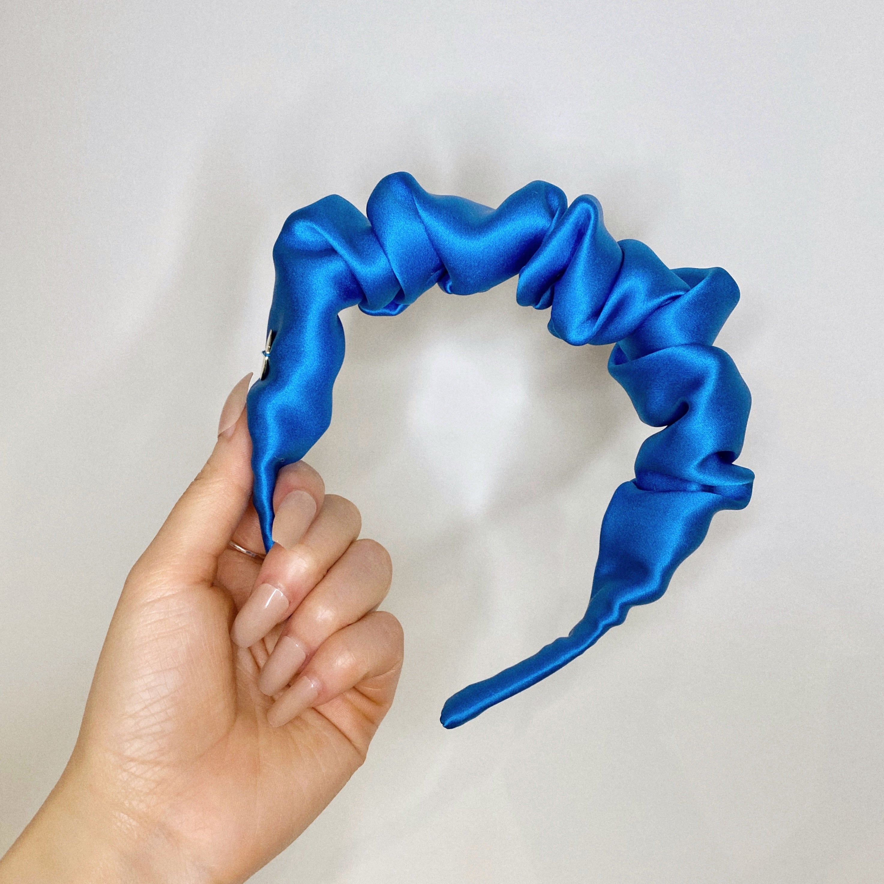Model holding a scrunchie headband in blue.