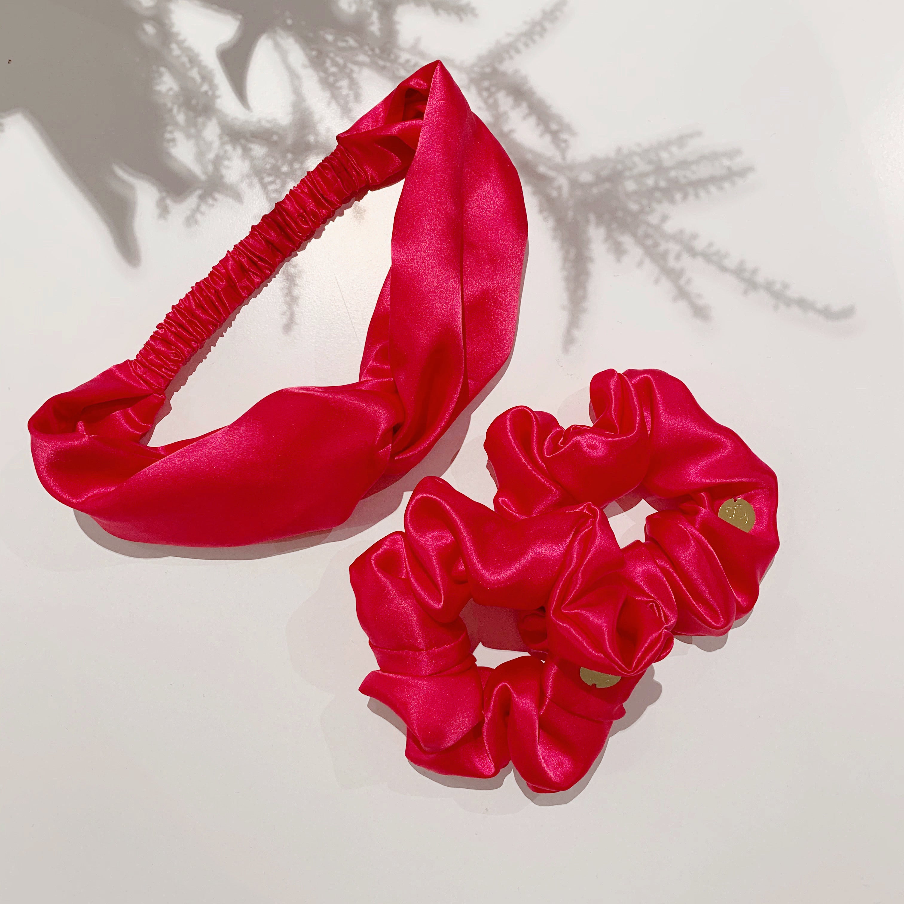 Flamingo - flat lay of 2 scrunchies and 1 twisted headband in fusia silk satin.