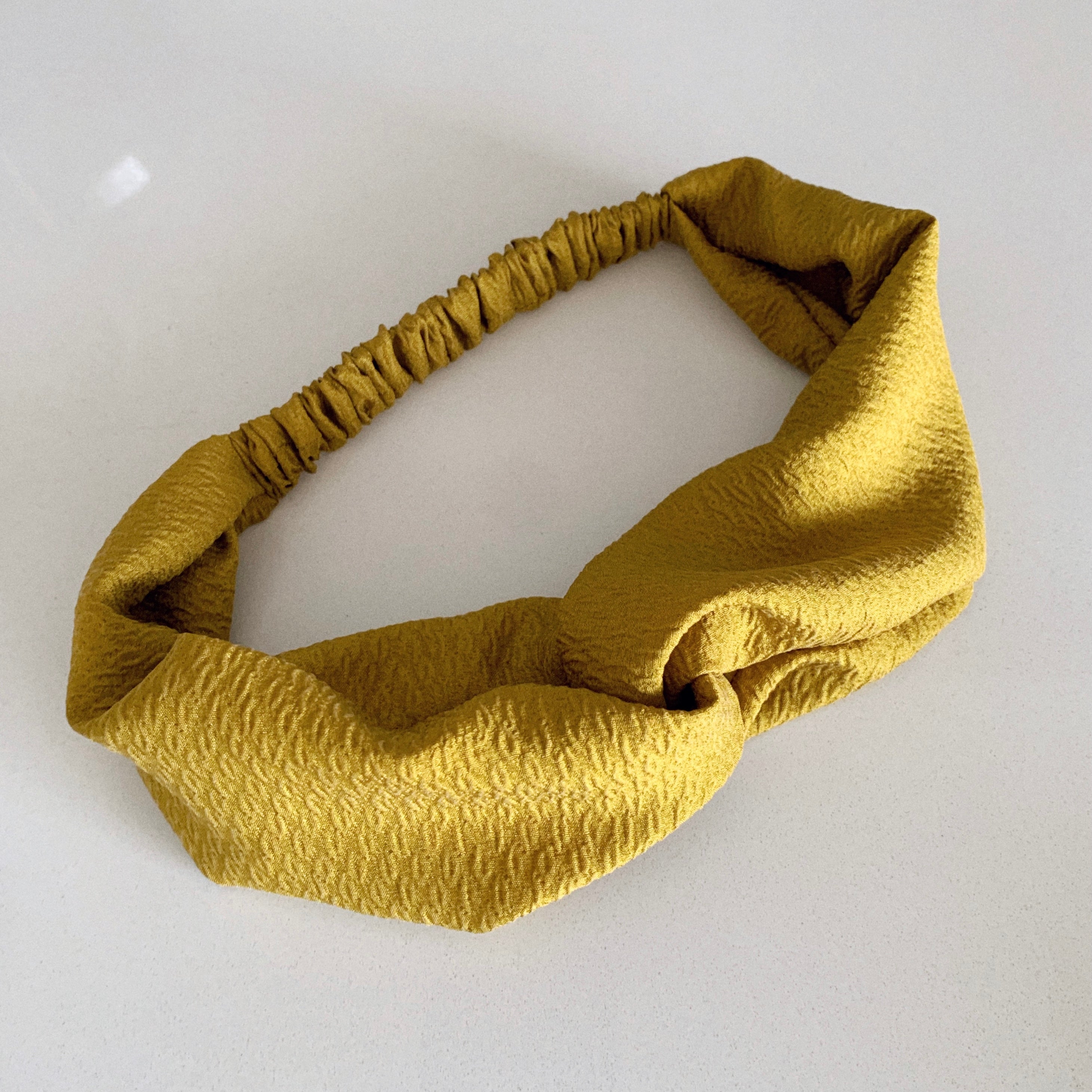 Flat lay of a twisted headband in Chartreuse.